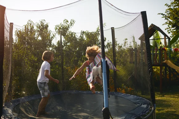 Zwei Kinder spielen auf einem Trampolin im Garten